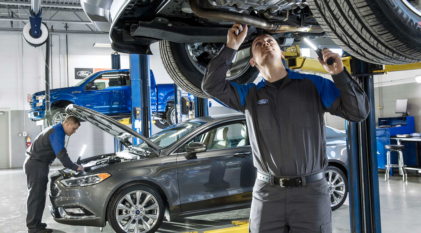 Mechanics working on vehicles in a professional Ford service center.